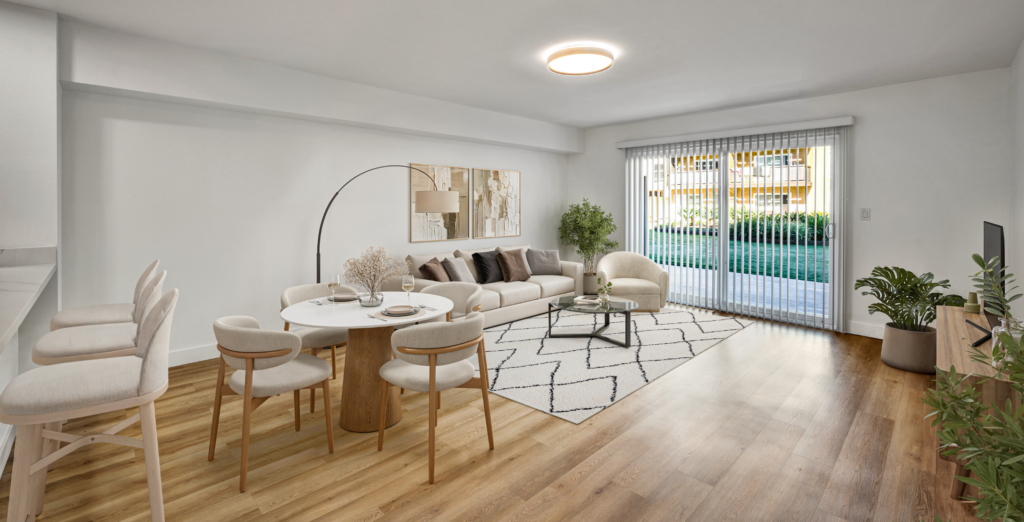 Bright modern apartment living and dining area with neutral furnishings, wood floors, and sliding glass doors to a patio.