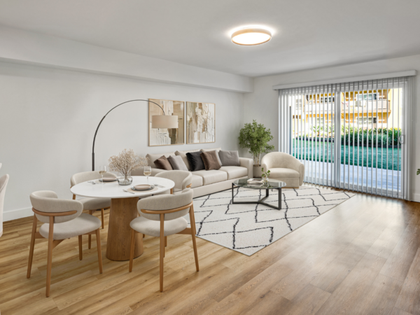 Bright modern apartment living and dining area with neutral furnishings, wood floors, and sliding glass doors to a patio.