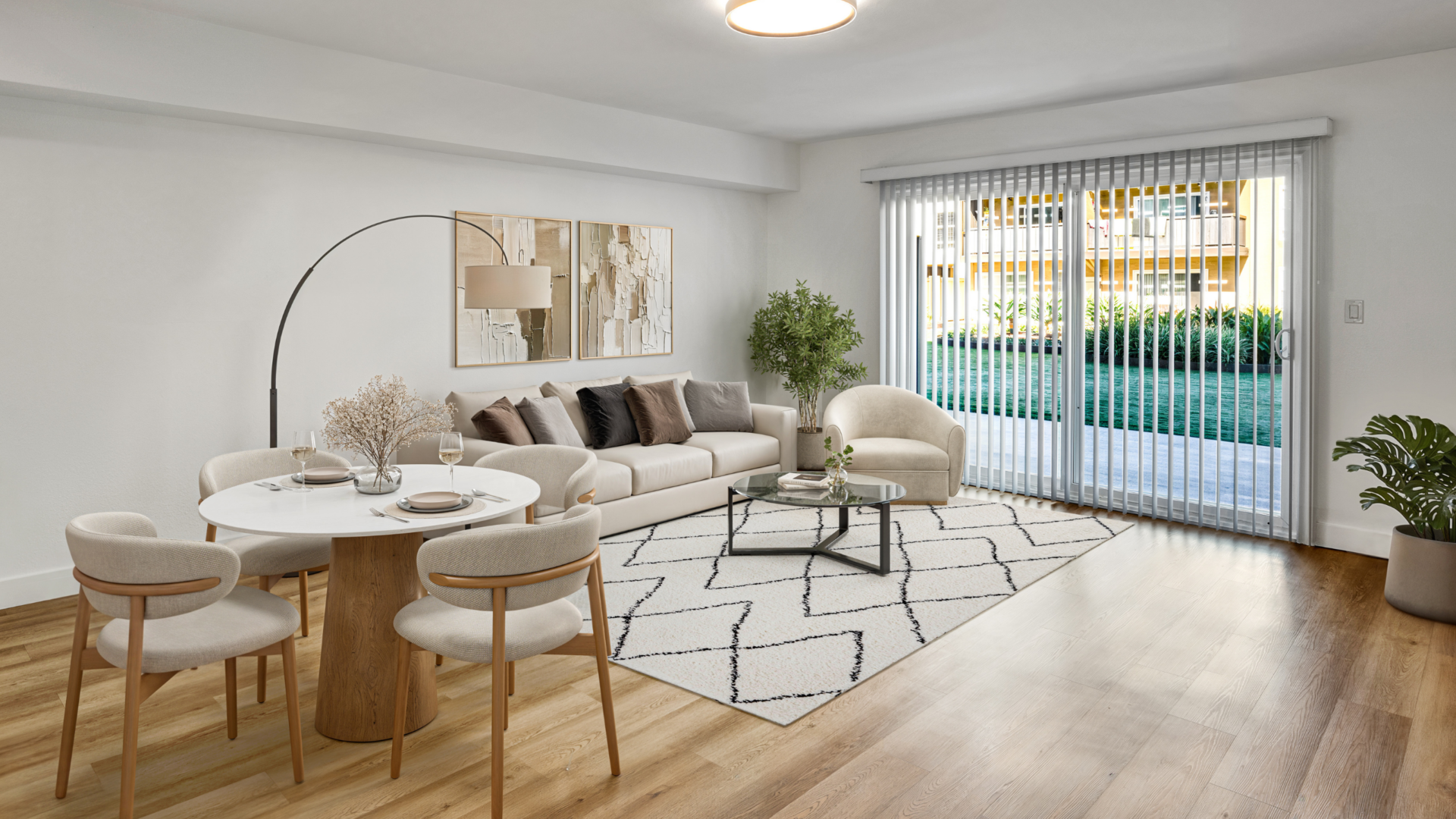 Bright modern apartment living and dining area with neutral furnishings, wood floors, and sliding glass doors to a patio.