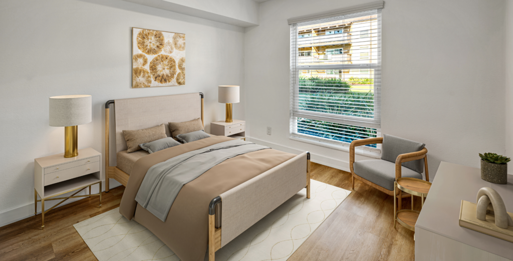 Bright bedroom with upholstered bed, nightstands, lamps, and large window overlooking greenery.
